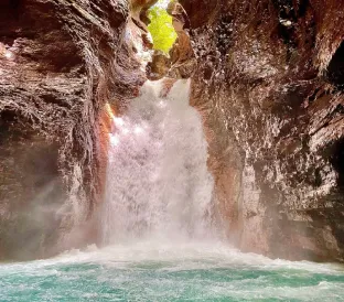 A turquoise river flows through a narrow rocky canyon surrounded by dense tropical vegetation.