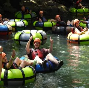 Two people tubing down a river surrounded by lush vegetation.