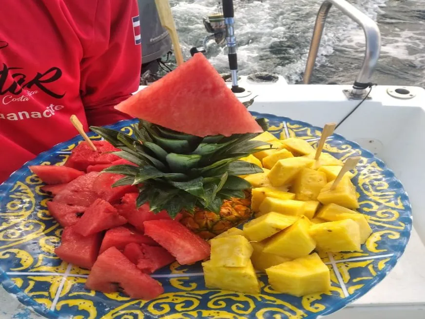 A colorful plate of fresh tropical fruits including watermelon, pineapple, and mango served on a boat.